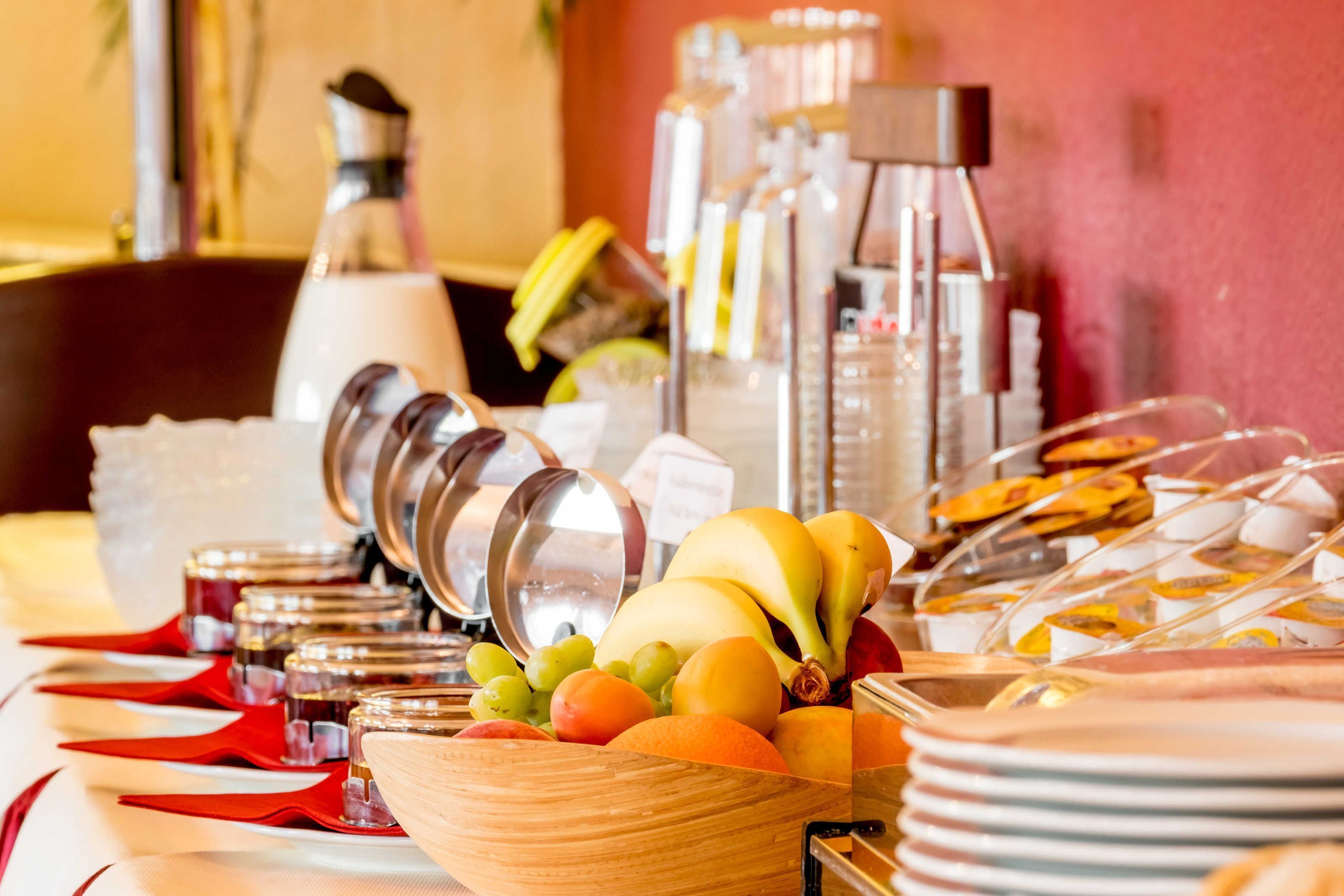 Een buffet met diverse soorten fruit, sauzen en bestek.