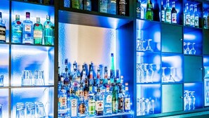 Un espace bar avec des étagères remplies de bouteilles d’alcool et de verres.