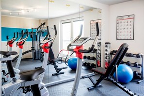 A gym with cardio machines, free weights, and exercise balls.