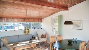 Quarto acolhedor com teto de madeira, uma janela grande com vista para um estacionamento, uma mesa verde e um banco.