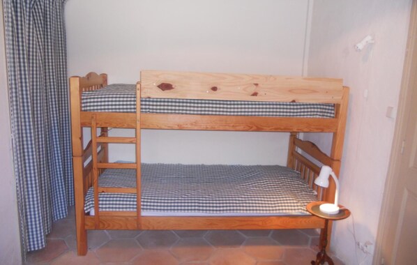 A bunk bed with checkered bedding, a bedside lamp, and a window with curtains.