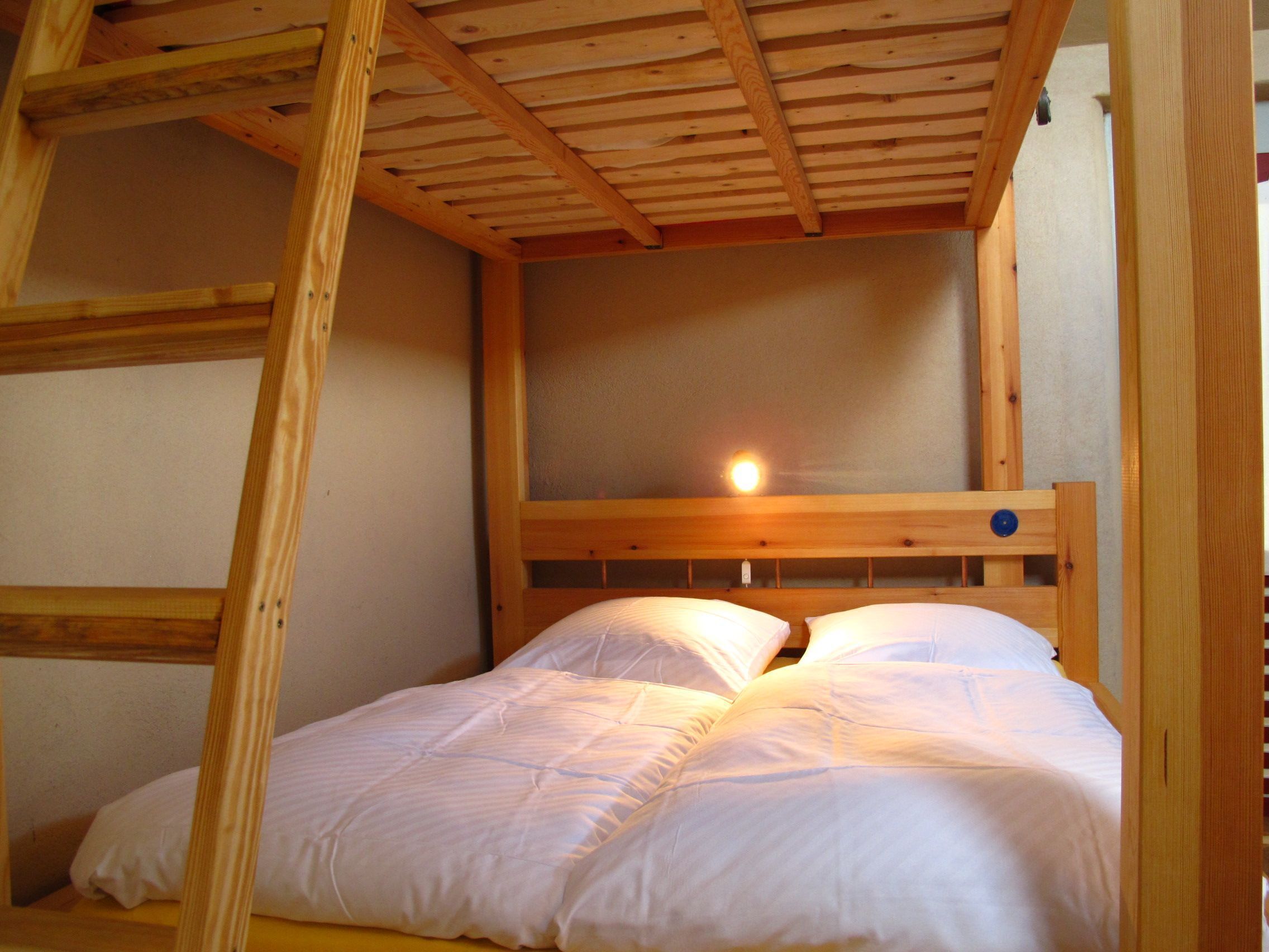 Una cama litera de madera con cabecera y una luz encima.