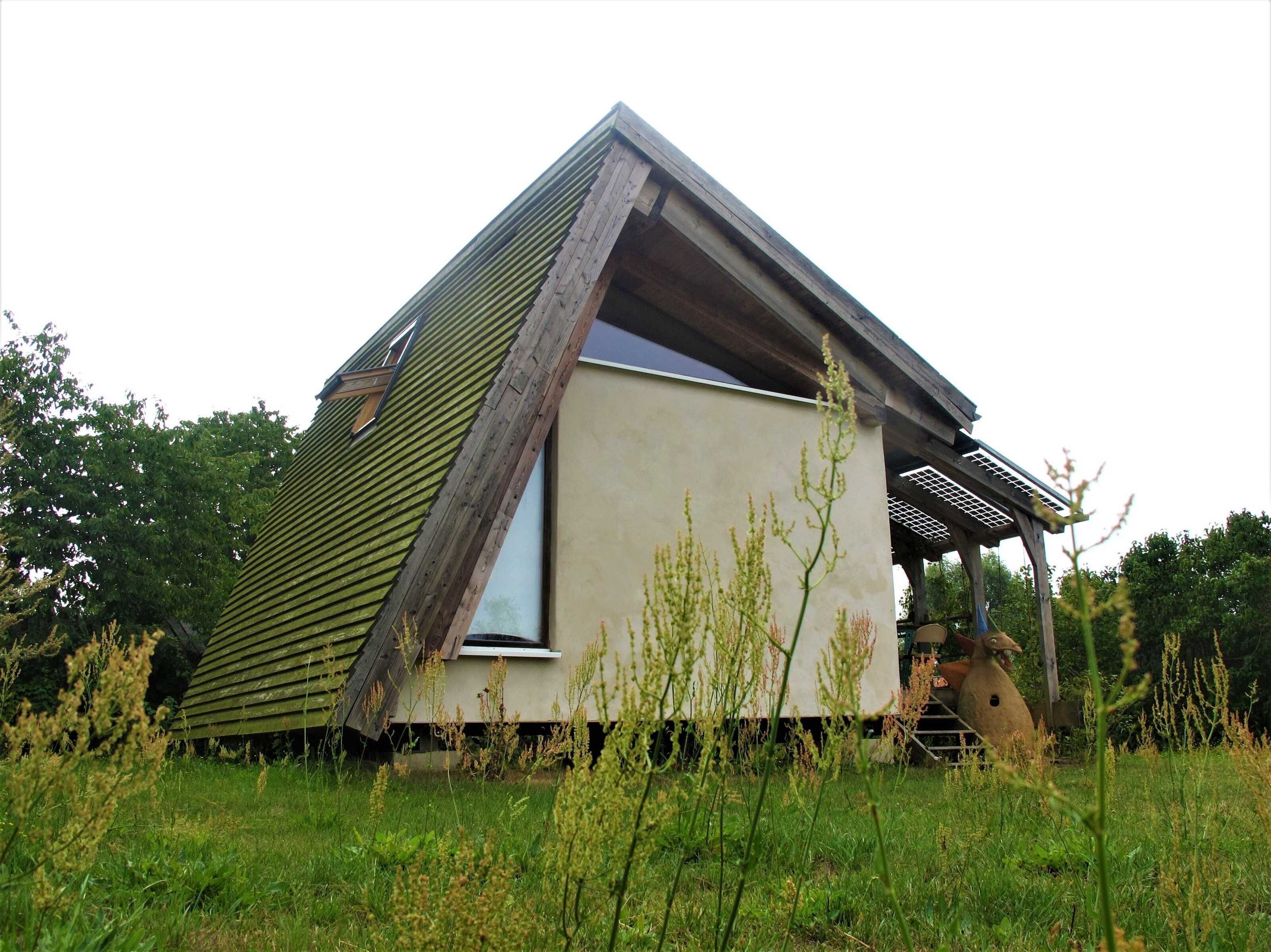 Een klein, gelijkvloers huis met schuine kap, een zichtbaar raam en een veranda.