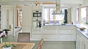 Een moderne keuken met witte kastjes, een inbouwoven en een groot raam.