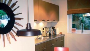 A modern kitchen with a pendant light, stainless steel appliances, and a window with a view of trees.