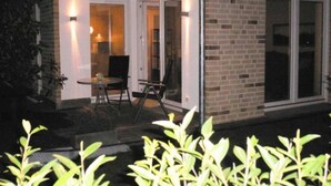 A building with a brick exterior, a glass door entrance, and a small patio area with a table and chairs.