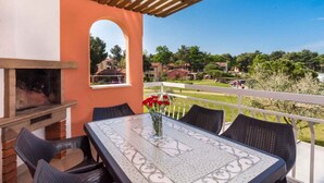 Une terrasse extérieure avec un barbecue, une table et des chaises, et une vue sur un quartier résidentiel.