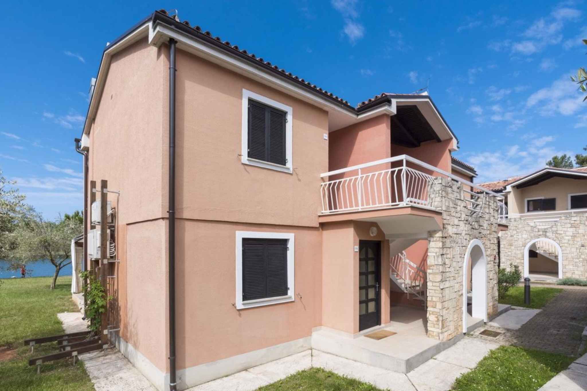 Un bâtiment à deux étages doté d’un balcon, d’une entrée en pierre et offrant une vue sur une étendue d’eau.