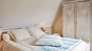 Un dormitorio con cama, almohadas, una lámpara de noche y un armario.