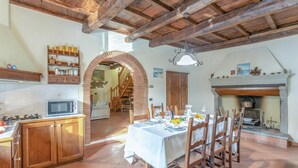 Un comedor rústico con chimenea de ladrillo, vigas de madera y piso de baldosas.