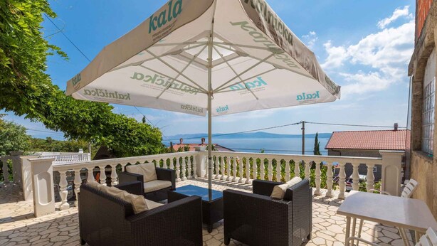 A terrace with wicker furniture, a table, and an umbrella branded 'KALNAKKA'. - Holiday apartment with air conditioning and WLAN (Crikvenica)