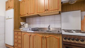 A kitchen with wooden cabinets, a white refrigerator, a stove, and a sink. - Holiday apartment with air conditioning and WLAN (Crikvenica)