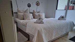 A bedroom with a bed, pillows, a blanket, and a wall decoration. - Apartment Bergblüte - FeWo (Bad Harzburg)