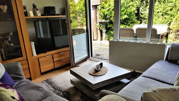 A living room with a sofa, a coffee table, and a television. - Apartment Bergblüte - FeWo (Bad Harzburg)