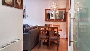 A dining area with a wooden table and chairs, a gray sofa, and a chandelier. - Apartment Bergblüte - FeWo (Bad Harzburg)