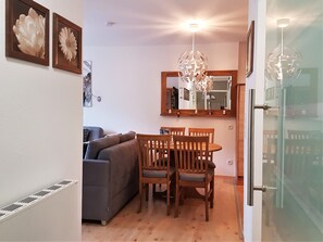 Un coin repas avec une table et des chaises en bois, un canapé gris et un lustre.