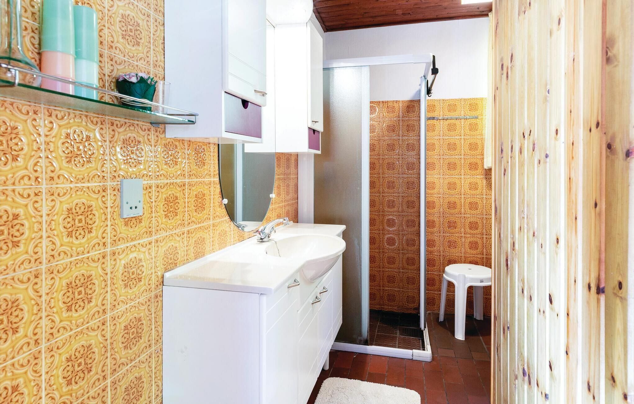 Une salle de bain avec des carreaux jaunes à motifs, un lavabo blanc et un espace douche.