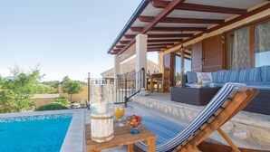 A poolside area with a lounge chair, a table with a drink and fruit, and a view of the pool. - Beautiful home in Prizba (Prizba)