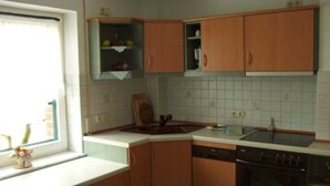 A kitchen with wooden cabinets, a dishwasher, and a window with a view. - Kräuter-Landhaus, Germany (Bad Schmiedeberg)