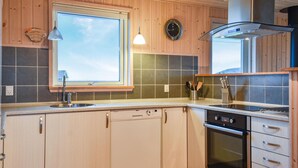 A modern kitchen with wooden cabinets, a built-in dishwasher, an oven, and a window with a view. - 3 bedroom stunning home in Harboøre (Harboøre)
