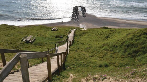 A wooden boardwalk leading to a beach with benches and a rocky outcrop. - 3 bedroom stunning home in Harboøre (Harboøre)