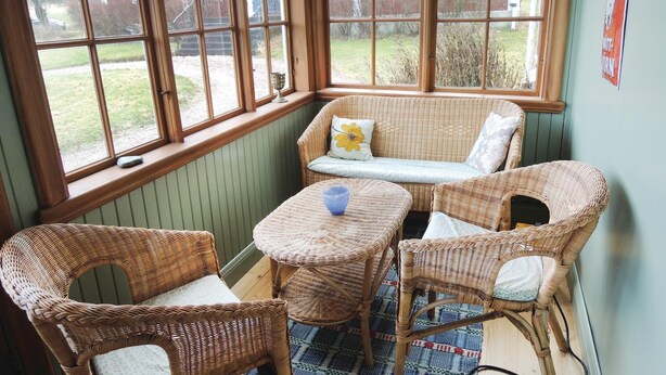 A corner room with wicker furniture, a blue glass bowl, and a view of a red barn through large windows. - 3 bedroom nice home in Tranås (Tranås)