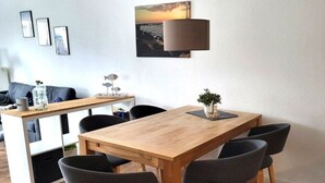A dining area with a wooden table and six chairs, a lamp, and a small plant on the table. - (171) 3- room apartment - apartment house Strandstr. 16 (Kühlungsborn)