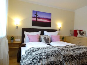 A double bed with a dark headboard, two bedside tables, a wall-mounted artwork, and a nightstand with a lamp. - Apartment for 6 persons Deluxe - Alpine jewel (Laimach)