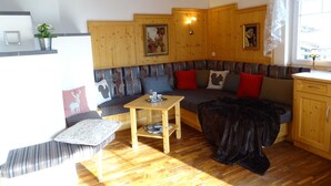 A cozy room with a wooden bench, a table, and a sofa with cushions. - Apartment for 6 persons Deluxe - Alpine jewel (Laimach)