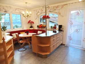 A kitchen with a dining area, a chandelier, a window with a view, and a refrigerator.
