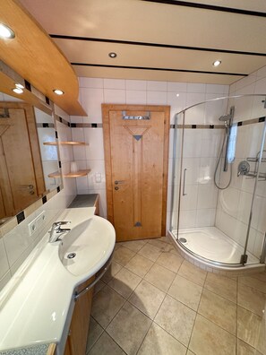 A bathroom with a wooden door, a sink, a shower, and a mirror. - Apartment for 6 persons Deluxe - Alpine jewel (Laimach)