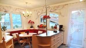 A kitchen with a dining area, a chandelier, a window with a view, and a refrigerator. - Apartment for 6 persons Deluxe - Alpine jewel (Laimach)