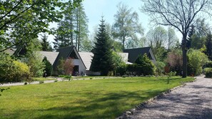 Une rangée de chalets modernes à un seul étage, dotés de toits inclinés, entourés d’une pelouse bien entretenue et d’arbres.