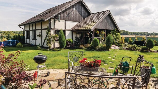 Et traditionelt bindingsværkshus med en velplejet have og udendørs siddeområde.