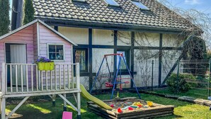 Et hus med et legeområde, der inkluderer en rutchebane og en gynge.