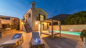 A stone villa with a pool, two lounge chairs, and a covered seating area. - Nice home in Kremena with sauna (Kremena)