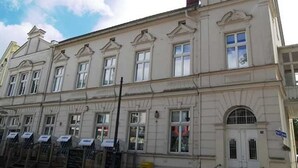 Un immeuble à plusieurs étages, de style architectural classique, caractérisé par des fenêtres disposées de manière symétrique et une entrée centrale.