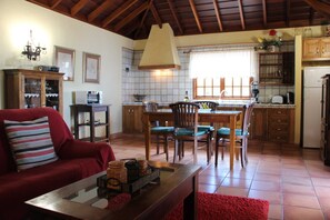 A cozy living room with a red sofa, a wooden coffee table, and a dining area with a wooden table and chairs.