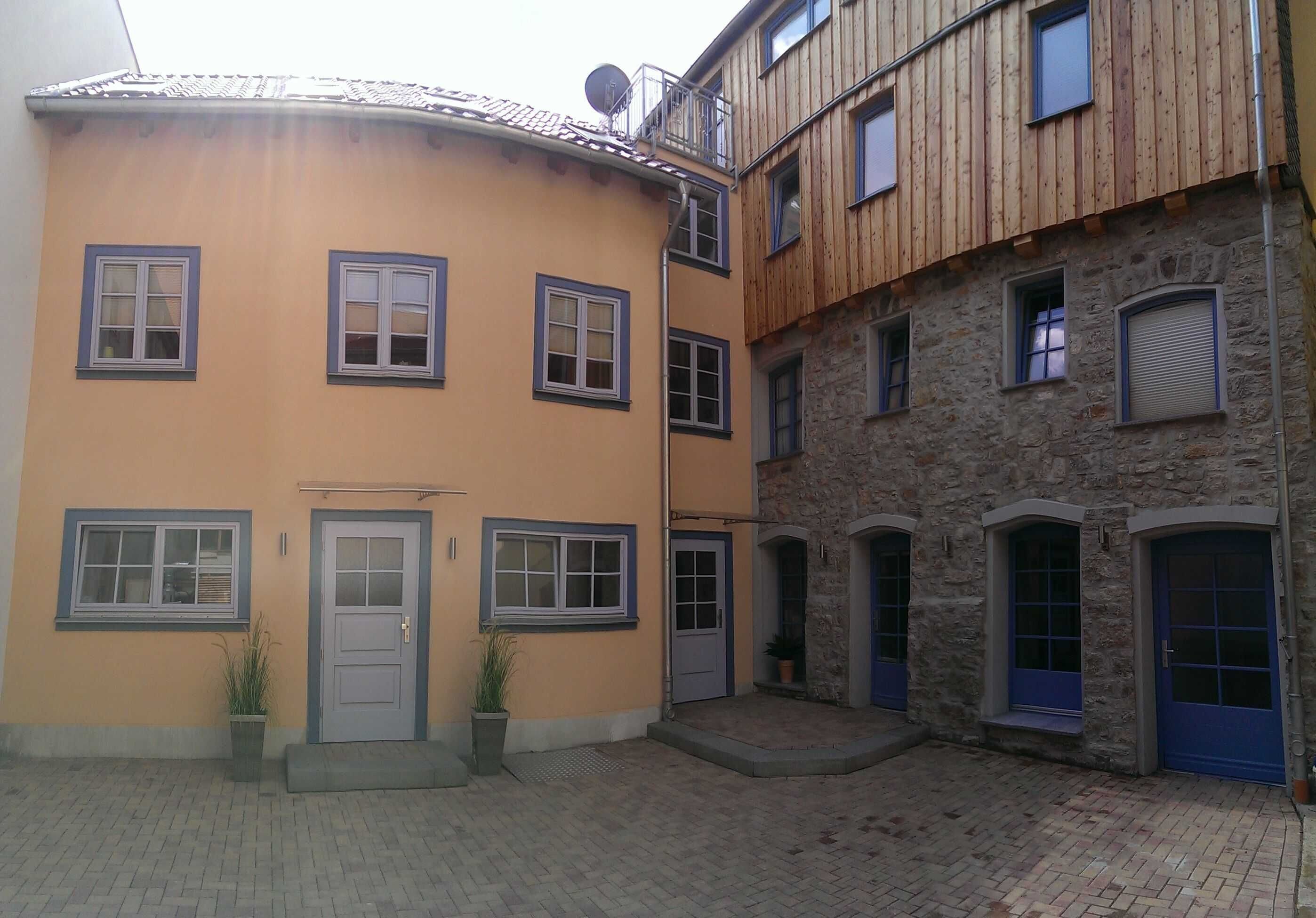 A courtyard with a yellow building, a stone building, and a blue door.