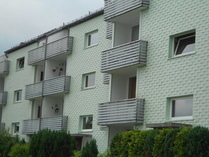 En flereetagers boligbygning med altaner, facade af mursten og fladt tag.