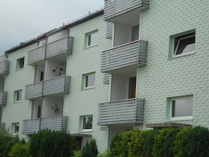 A multi-story residential building with balconies, a brick facade, and a flat roof.