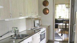 A modern kitchen with white cabinets, a stainless steel sink, and a stove. There is a dining area with a round table and chairs.