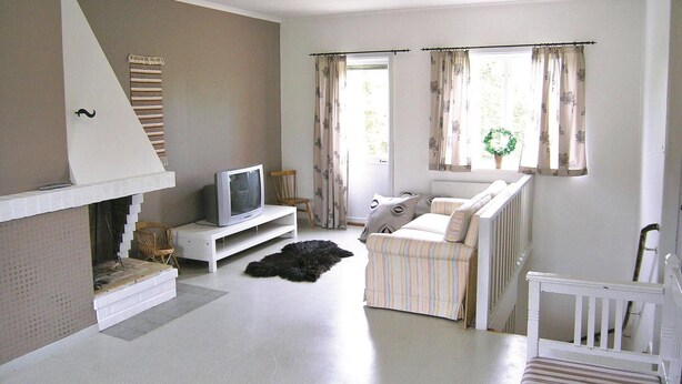 A living room with a fireplace, a television, a sofa, and a window with curtains.