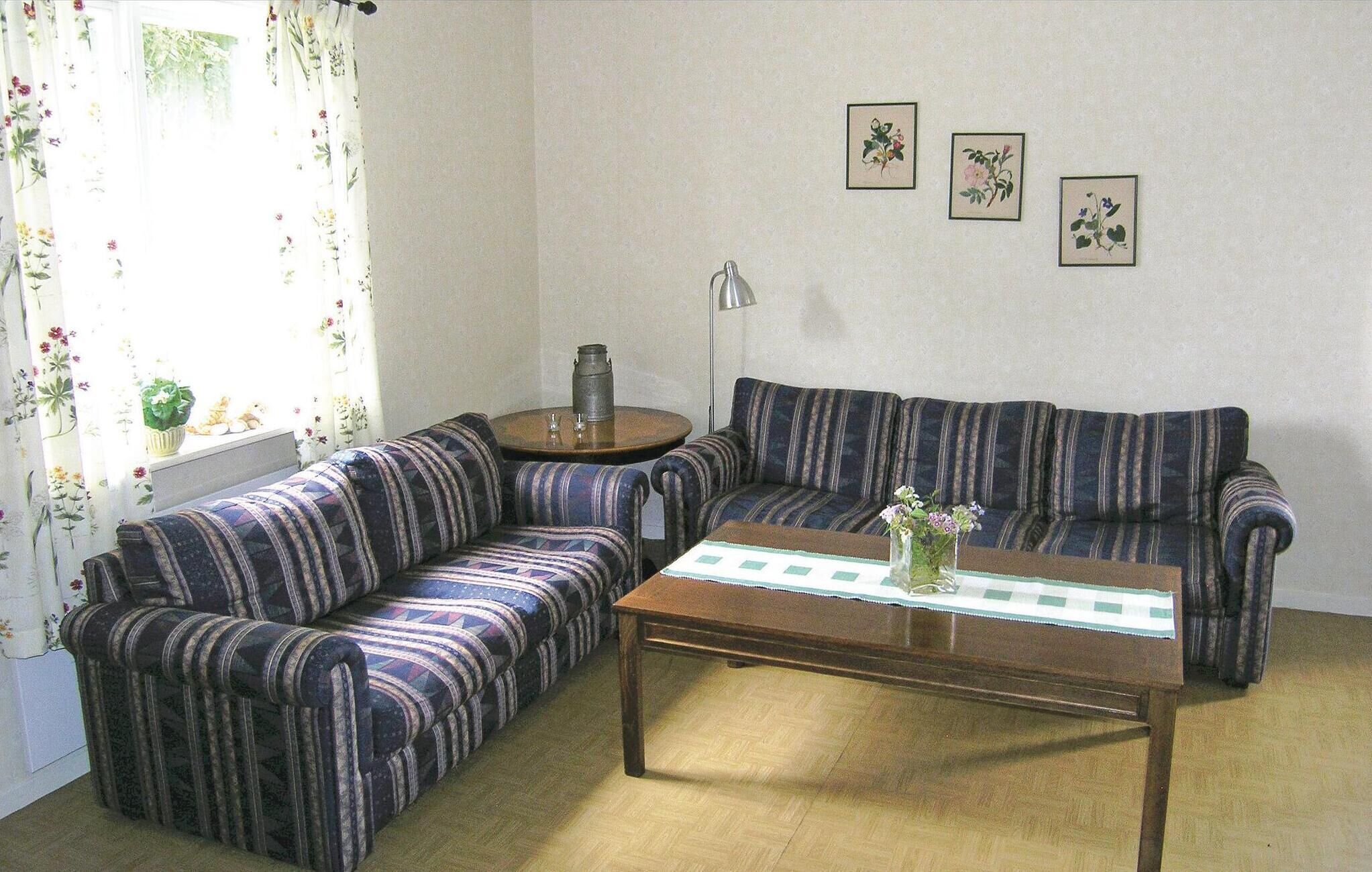 Un saló amb sofàs estripats, una taula de centre, una làmpada i cortines amb motius florals.