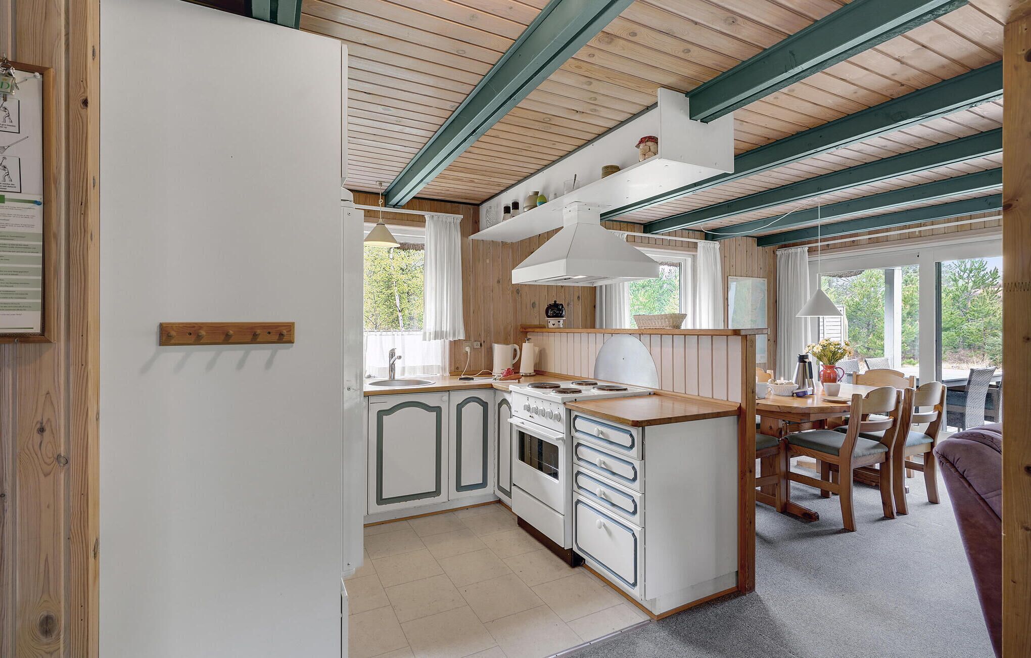 A kitchen with wooden cabinets, a stove, and a dining area with chairs and a table.