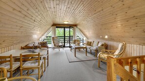 A cozy attic room with wooden walls and a sloped ceiling, furnished with a dining table, chairs, and a sofa. - 3 bedroom cozy home in Rømø (Rømø)