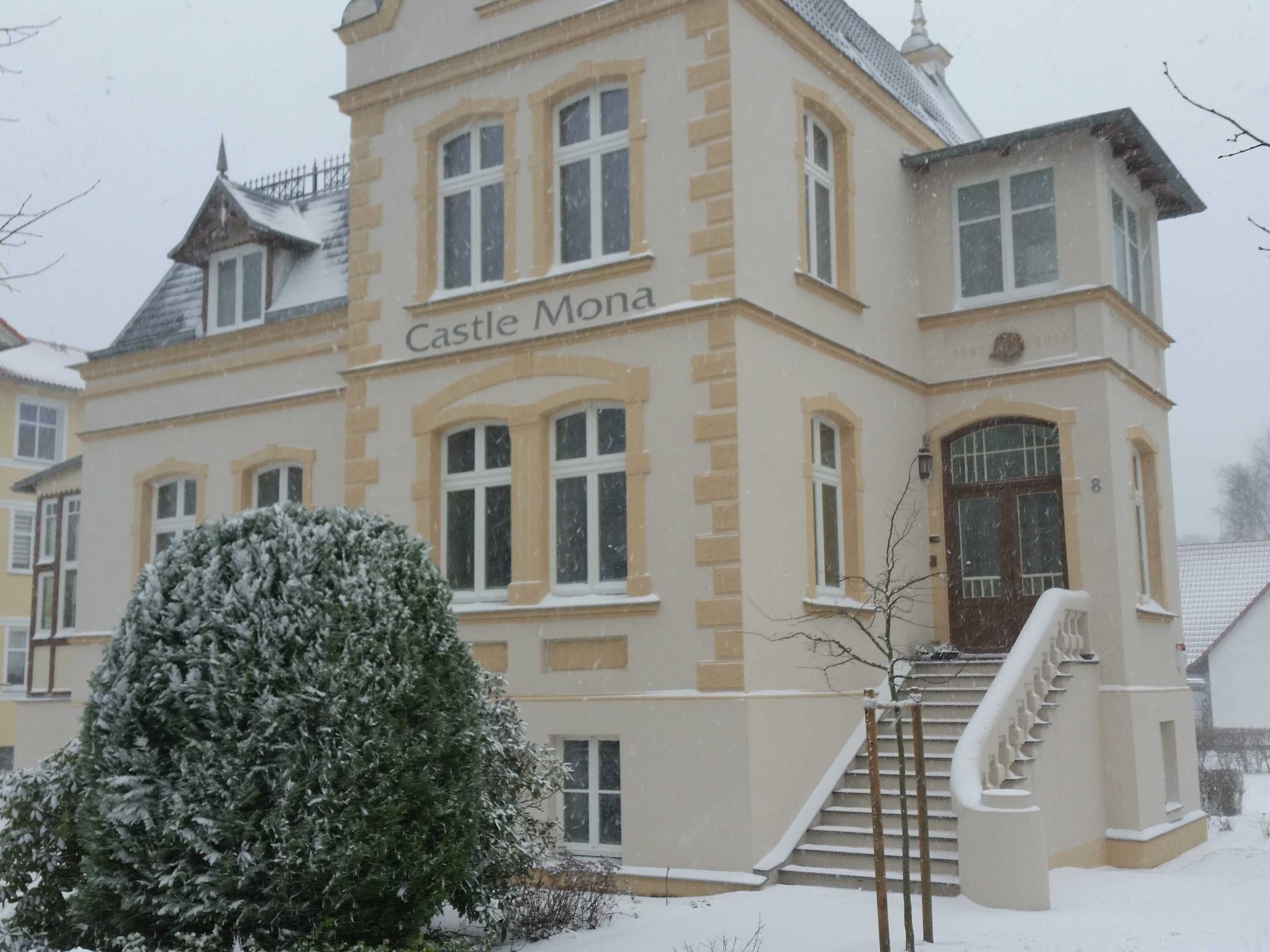 A large, historic building labeled 'Castle Mona' with a prominent entrance and a staircase leading to the main entrance.