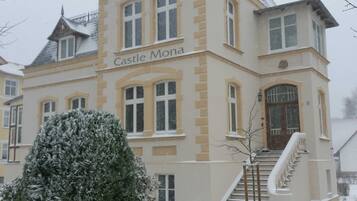 A large, historic building labeled 'Castle Mona' with a prominent entrance and a staircase leading to the main entrance.