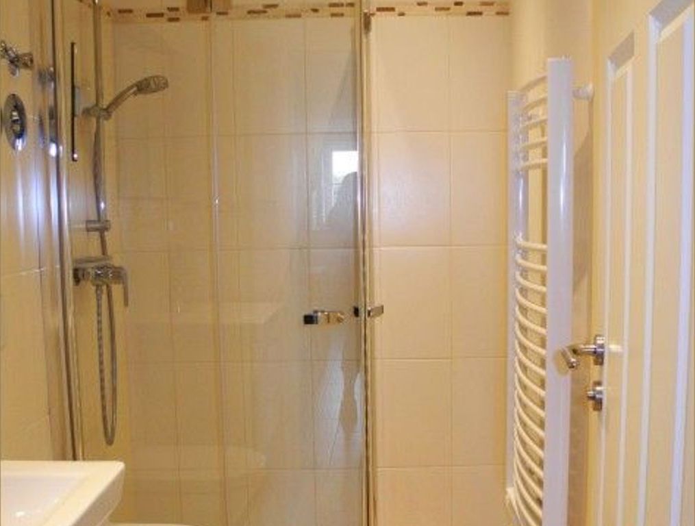 Ein Badezimmer mit Duschkabine aus Glas, einem weißen Waschbecken und einem Handtuchhalter.