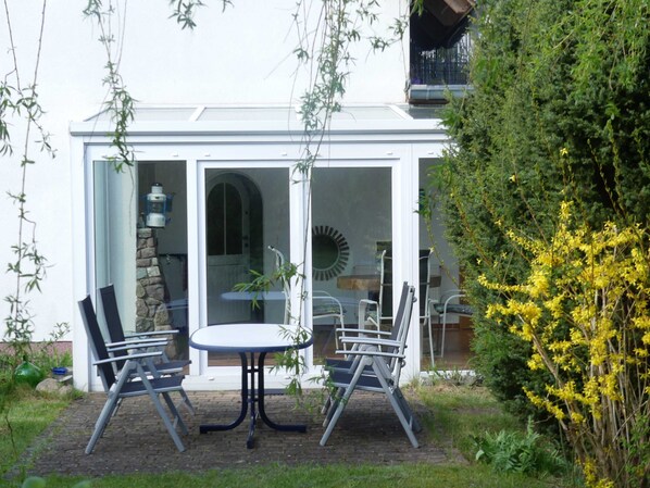 A conservatory with a table and chairs, a stone wall, and a glass door. - Schiel apartment rental - Apartment (Zempin)